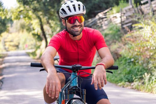 young cyclist smiling happy as he rests sitting on his mountain bike after training, concept of freedom and sport in nature, copy space for text