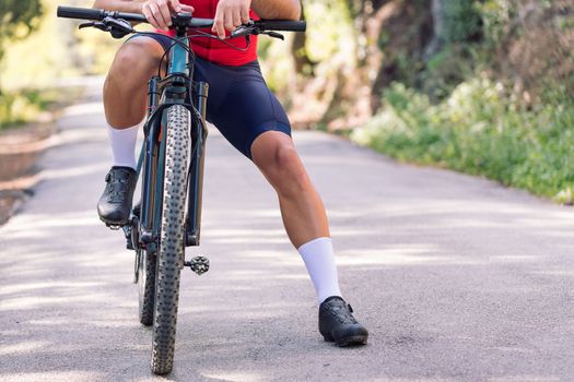 legs of an unrecognizable cyclist loading the route on his mountain bike navigator to go for a training ride, concept of freedom and sport in nature, copy space for text