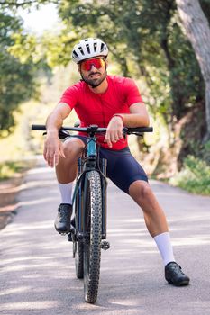 young cyclist resting sitting on his mountain bike after training, concept of freedom and sport in nature, copy space for text