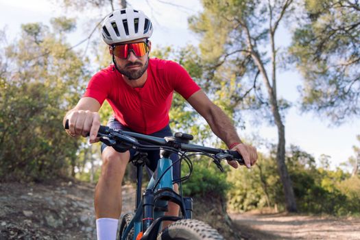young cyclist training hard in the forest with his mountain bike, concept of freedom and sport in nature, copy space for text