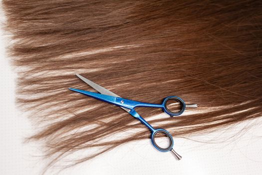 Scissors lie on the hair ribbon for extension at home. Hair extensions to thicken your own. Individual strands of hair close-up