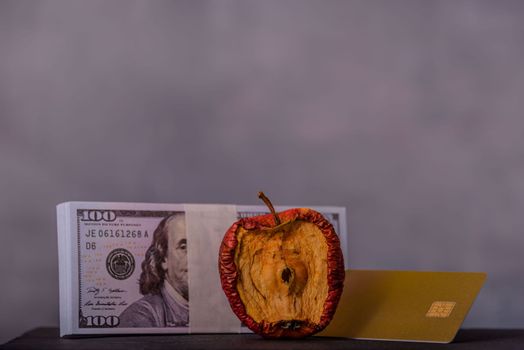 A conceptual image centered on a bad apple, money and credit card for various monetary ideas