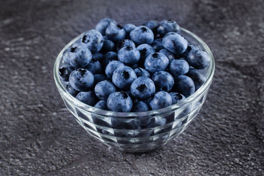 Blueberries organic natural berry on dark background. Blueberry in glass bowl plate
