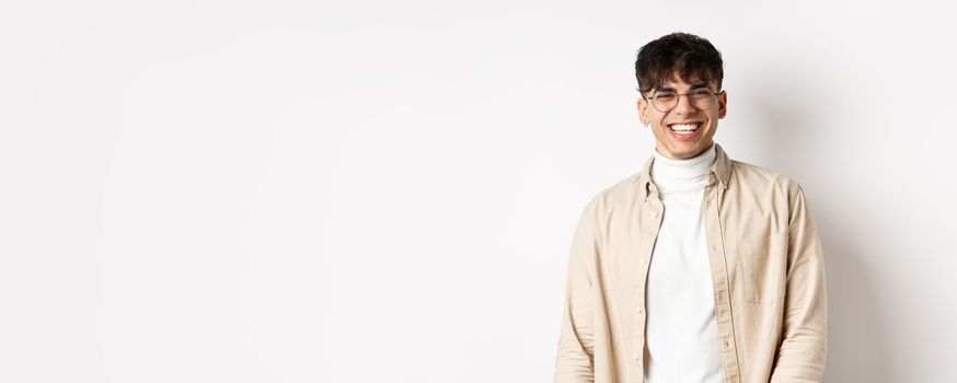 Real people. Natural portrait of happy guy smiling and laughing, looking upbeat at camera, standing in glasses on white background.