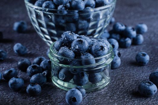 Blueberries organic natural berry with water drops on dark background close-up. Blueberry in glass bowl plate