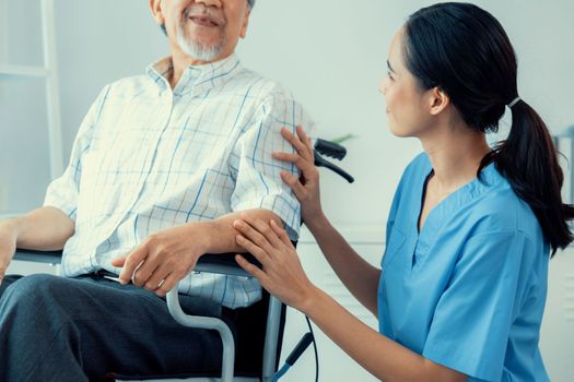 Happy positive asian nurse giving support and touching contented senior man with love. Nursing home for the elderly, elderly health and illness, senior patient carer.