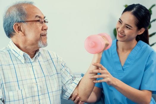 Contented senior patient doing physical therapy with the help of his caregiver. Senior physical therapy, physiotherapy treatment, nursing home for the elderly