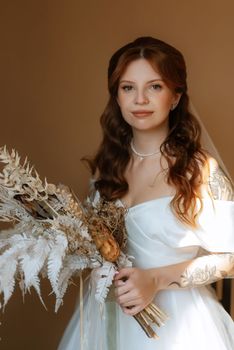 portrait of a bride girl with red hair in a white wedding dress with a bouquet