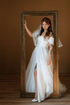 portrait of a bride girl with red hair in a white wedding dress with a bouquet