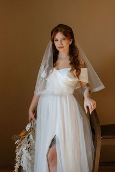 portrait of a bride girl with red hair in a white wedding dress with a bouquet