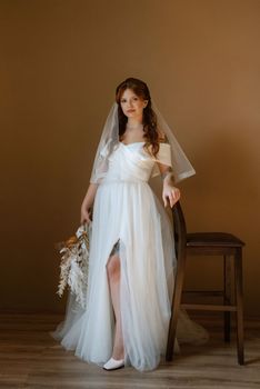 portrait of a bride girl with red hair in a white wedding dress with a bouquet