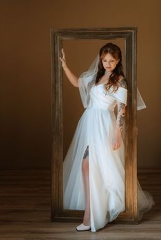 portrait of a bride girl with red hair in a white wedding dress with a bouquet