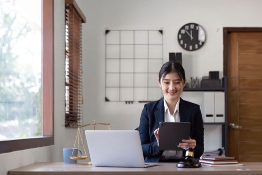 Attractive young lawyer in office Business woman and lawyers discussing contract papers with brass scale on wooden desk in office. Law, legal services, advice, Justice and real estate concept.