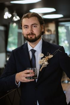 portrait of a male groom in a blue suit in the morning going to the barbershop on the wedding day