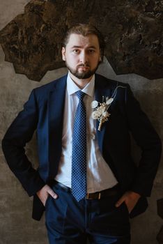 portrait of a male groom in a blue suit in the morning going to the barbershop on the wedding day