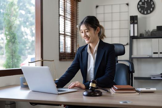 Attractive young lawyer in office Business woman and lawyers discussing contract papers with brass scale on wooden desk in office. Law, legal services, advice, Justice and real estate concept.