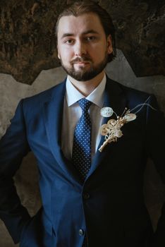 portrait of a male groom in a blue suit in the morning going to the barbershop on the wedding day