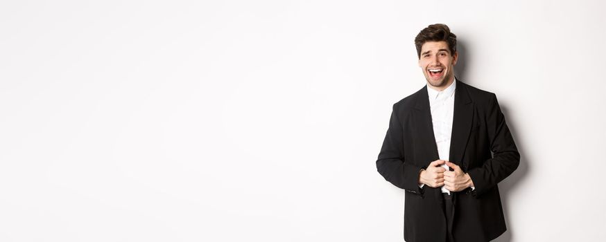 Concept of new year party, celebration and lifestyle. Portrait of handsome and confident man in suit, smiling pleased, feeling successful, standing over white background.