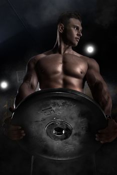 Attractive tall muscular bodybuilder doing heavy deadlifts in moder fitness center, creative photo, contours, muscles stand out, beautiful body, physique, relief, sexy guy, young.