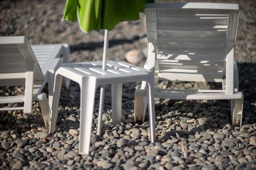 Several white sun loungers and an umbrella on a deserted beach. The perfect vacation concept