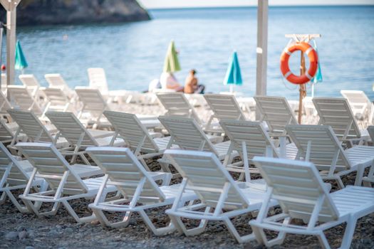 Several white sun loungers and an umbrella on a deserted beach. The perfect vacation concept