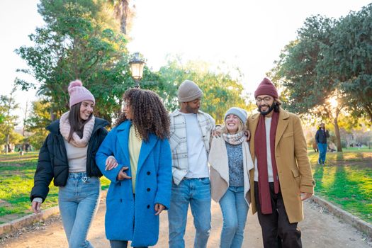 Cheerful group of students walking outdoors in the park of the campus University college having fun together. Erasmus bridge multiracial colleagues friendship. High quality photo