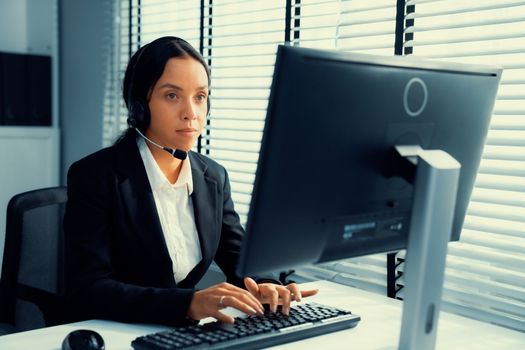 Competent female operator working on computer and talking with clients. Concept relevant to both call centers and customer service offices.