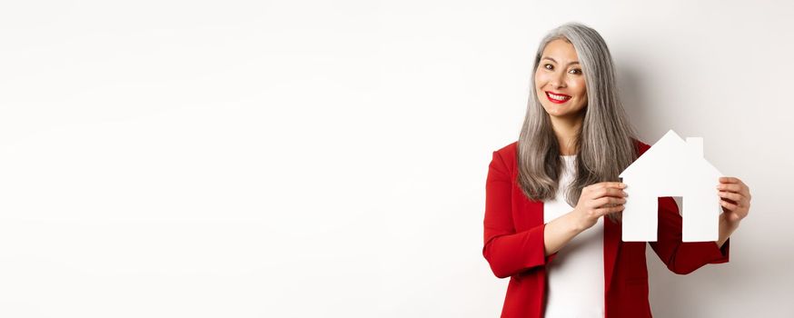 Smiling real estate agent showing paper house clipboard, broker working with client, standing over white background.