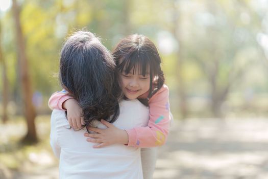 Asian Grandmother and Granddaughter hug together outdoor park. Hobbies and leisure, lifestyle, family life, happiness moment concept.