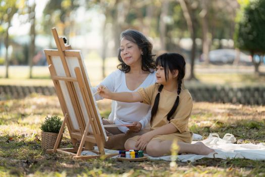 Asian Grandmother and Granddaughter having activity together outdoor park. Hobbies and leisure, lifestyle, family life, happiness moment concept.