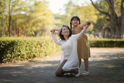 Asian Grandmother and Granddaughter having activity together outdoor park. Hobbies and leisure, lifestyle, family life, happiness moment concept.