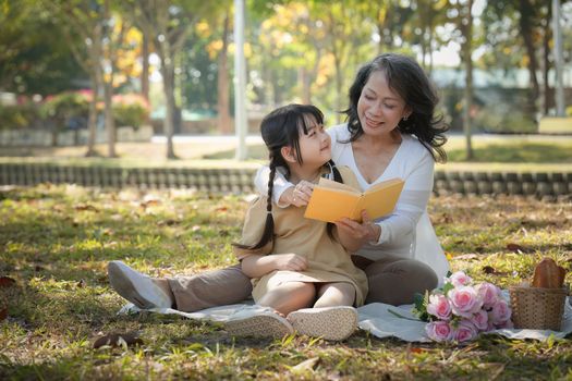 Asian Grandmother and Granddaughter having activity together outdoor park. Hobbies and leisure, lifestyle, family life, happiness moment concept.