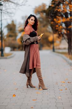 A woman walks outdoors in autumn, enjoys the autumn weather