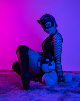 sexy girl in costume and mask bdsm games in neon light with empty background