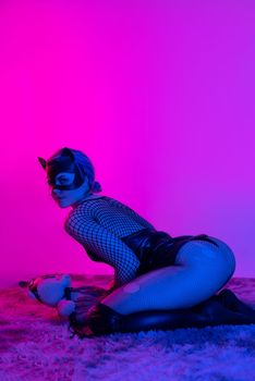 sexy girl in costume and mask bdsm games in neon light with empty background