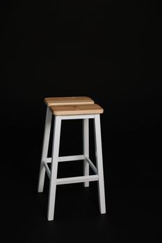 minimalistic wooden chair against black background. Concept modern interior and design furniture in room. High stool in loft style. Retro Bar chair. Vintage wooden metal chair