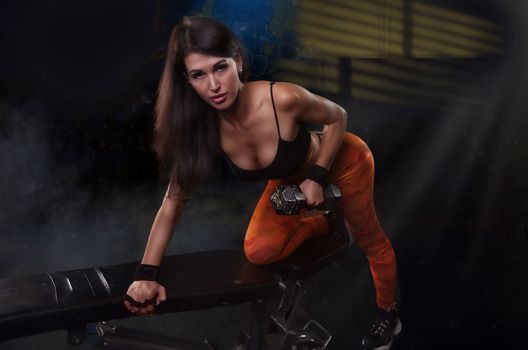 Strong woman doing weights.Sports lifestyle Beautiful fitness woman lifting dumbbells . Fitness sporty woman showing her well trained body. A beautiful girl's body with rippling muscles from strength training. High quality photo