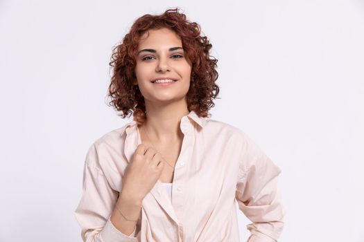 Sincere smile of a young European woman. Attractive girl with short chestnut-colored hair. Naturally curly hair.