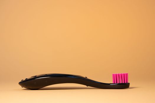 Neon pink plastic baby tooth brush on natural background. Dental and healthcare concept