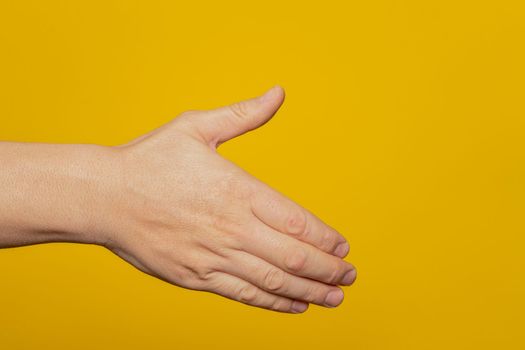 Man stretching out his hand to handshake isolated on a yellow background. Man's hand ready for handshake. Alpha