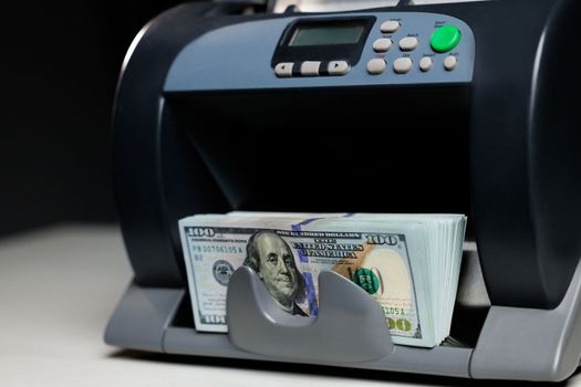 Closeup of cash counting machine counting dollar bills. Business accounting and commercial activity, american monetary units. Counting machine with US national cash money.
