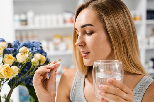 Girl with Omega-3 capsule and cup of water is ready to take a BADS capsule of Omega-3. Biologically active dietary supplements. Taking vitamin D for building and maintaining healthy bones