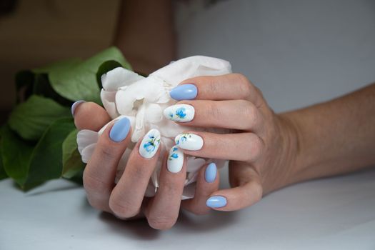 girl with a beautiful white blue manicure with a bouquet of delicate peonies, . High quality photo