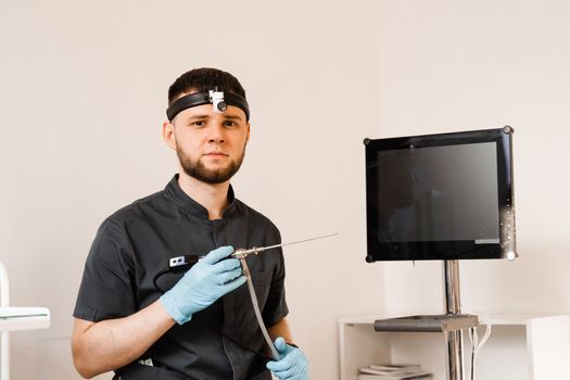 ENT doctor otolaryngologist with endoscope in hands. Prepearing for endoscopy procedure. Doctor with headlight