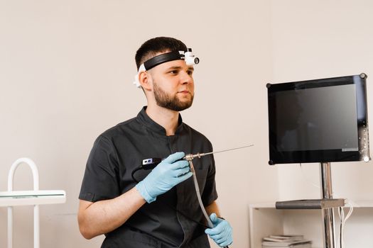 ENT doctor otolaryngologist with endoscope in hands. Prepearing for endoscopy procedure. Doctor with headlight