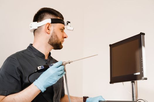 ENT doctor otolaryngologist with endoscope in hands. Prepearing for endoscopy procedure. Doctor with headlight