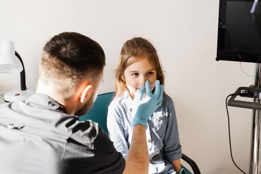 Nose examination of the child. Consultation of kid with a pediatric otolaryngologist in a medical clinic