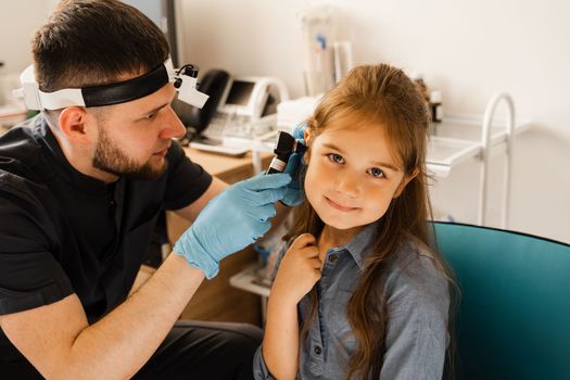 ENT doctor otolaryngologist looks through otoscope the ears of a little girl. Otoscopy. Treatment child ear pain