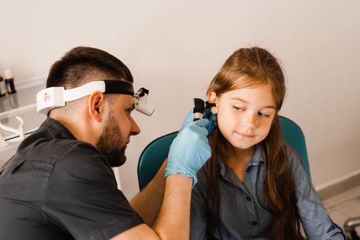 ENT doctor with otoscope. Otoscopy. Pediatrician otolaryngologist looks through otoscope the ears of child. Otoscopy. Treatment ear pain