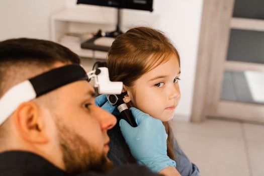 ENT doctor with otoscope. Otoscopy. Pediatrician otolaryngologist looks through otoscope the ears of child. Otoscopy. Treatment ear pain